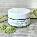 Closed jar of Dermotechnology Matcha Clay Mask with matcha powder and aloe vera on a wooden surface